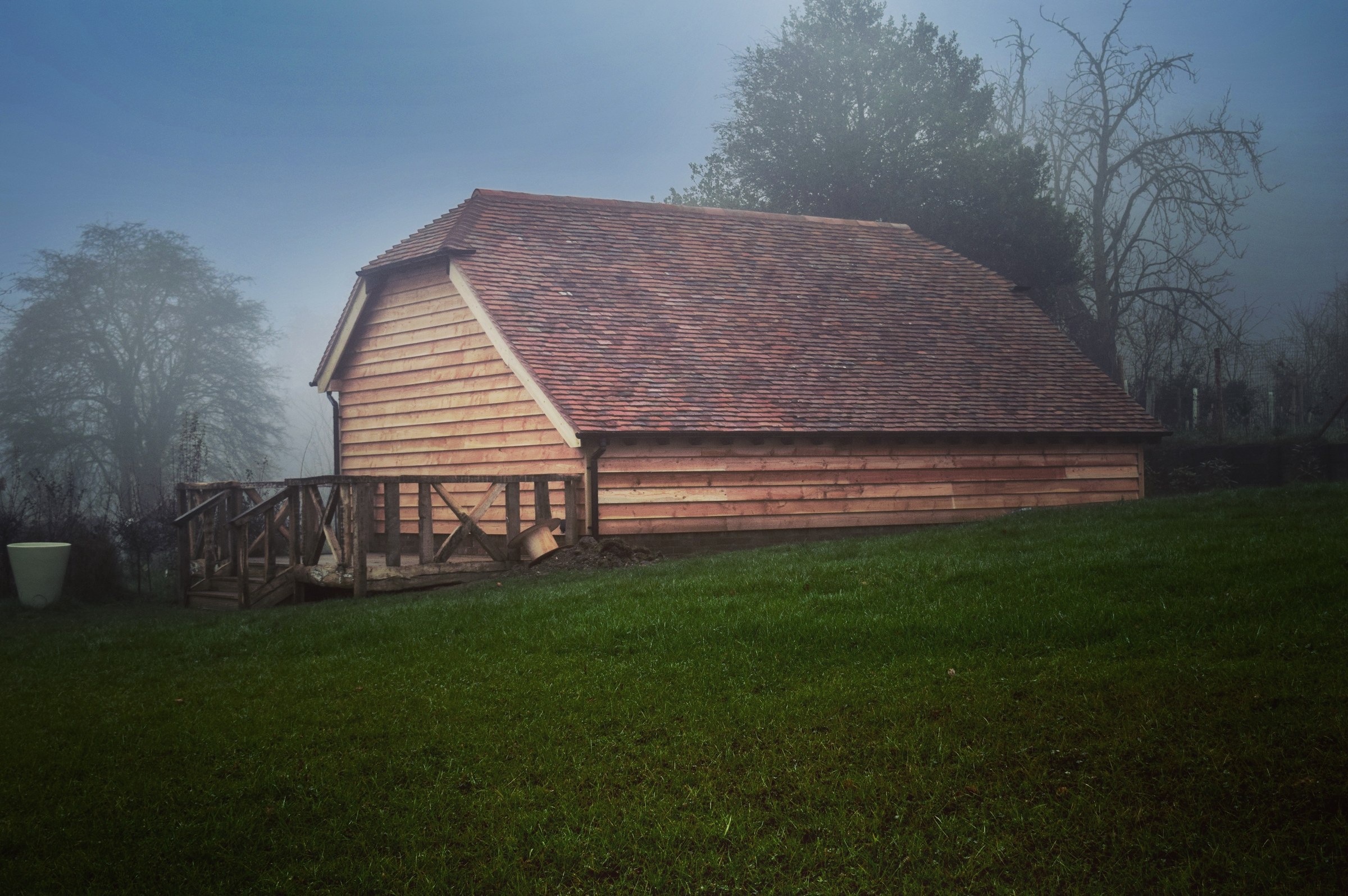 An oak-framed garage at dusk, its timbers lit from within